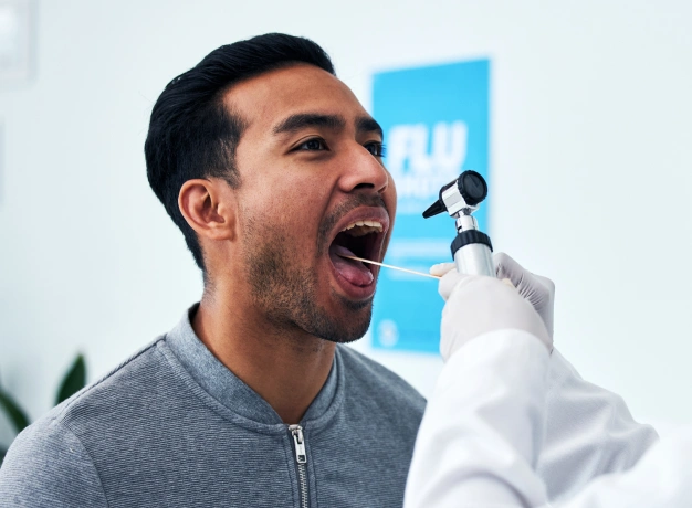 Man receiving dental examination from dentist in white coat at dental office.