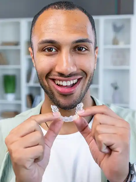 a young male dental patients attaching Invisalign aligners to his teeth